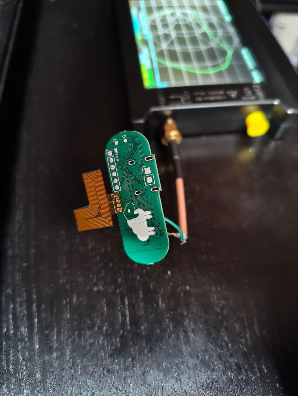 The NFC antenna connected to the LiteVNA on the board, with Cloudy watching the experiment.